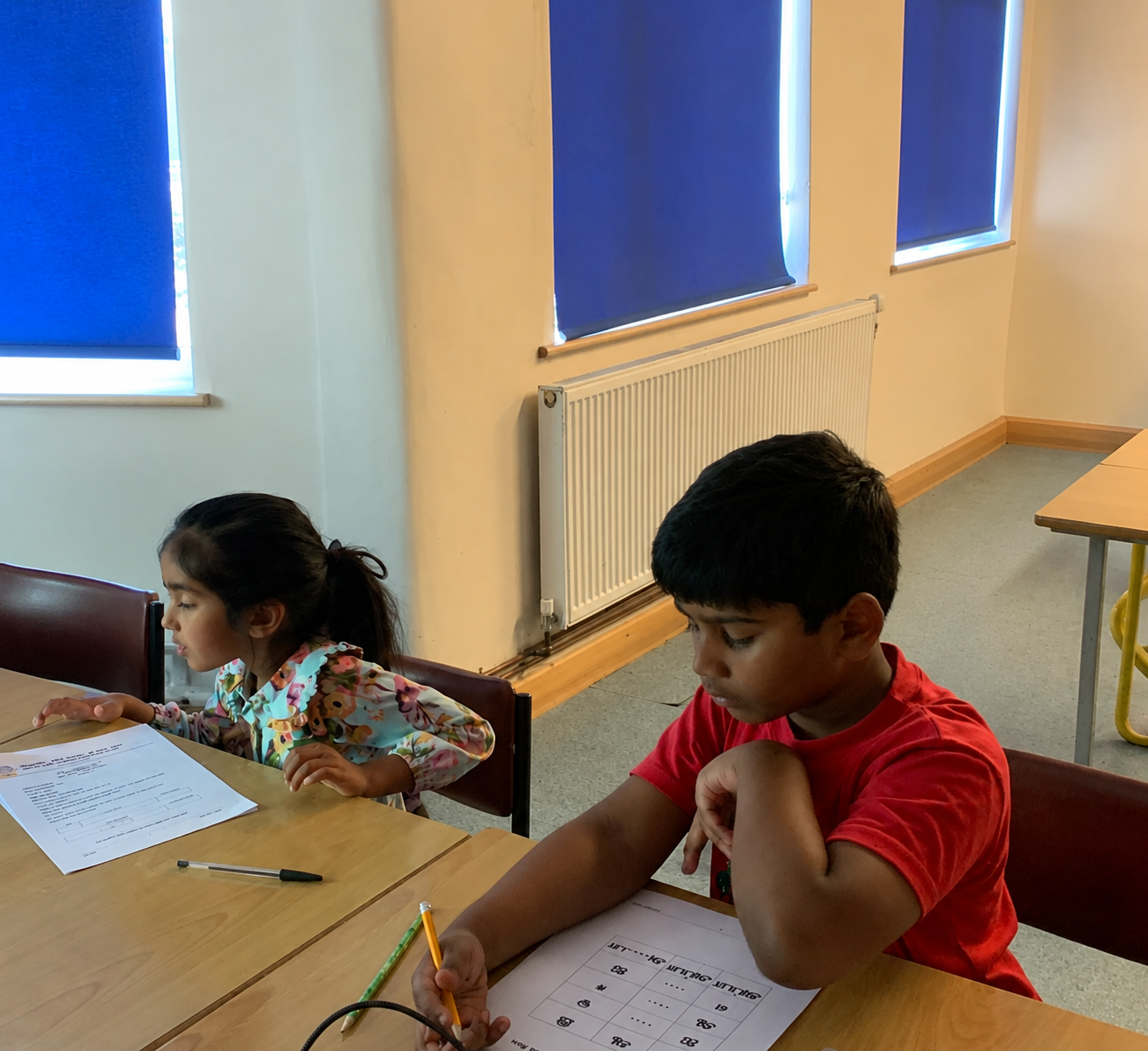 Children completing Tamil certification work at a table